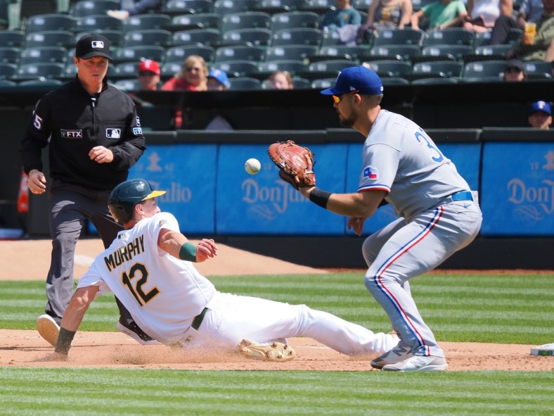 Apr 24, 2022; Oakland, California, USA; Oakland Athletics catcher Sean Murphy (12) dives safely back to first base against Texas Rangers first baseman Nathanial Lowe (30) during the fourth inning at RingCentral Coliseum. Mandatory Credit: Kelley L Cox-USA TODAY Sports
