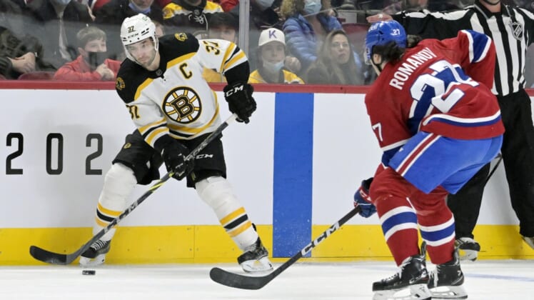 Apr 24, 2022; Montreal, Quebec, CAN; Boston Bruins forward Patrice Bergeron (37) plays the puck and Montreal Canadiens defenseman Alexander Romanov (27) defends  during the first period at the Bell Centre. Mandatory Credit: Eric Bolte-USA TODAY Sports