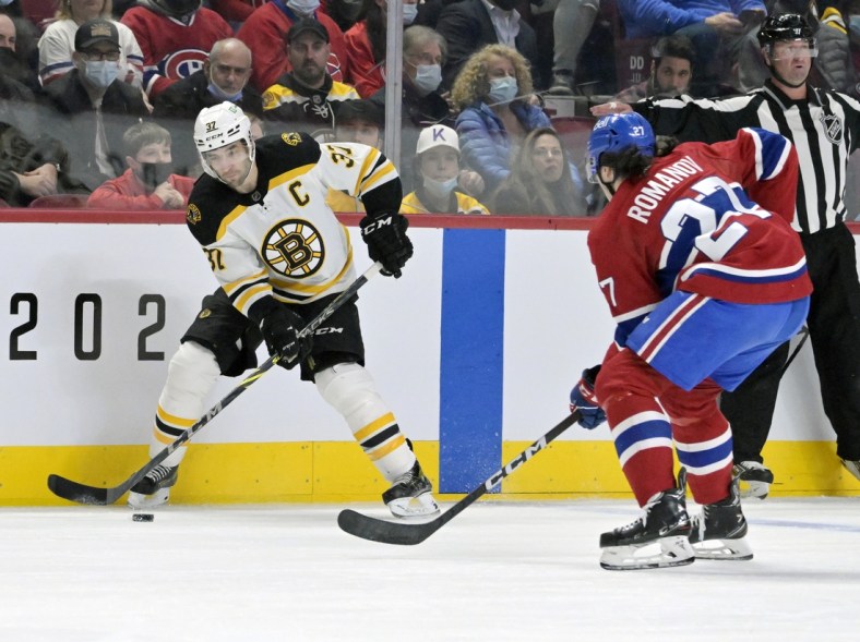 Apr 24, 2022; Montreal, Quebec, CAN; Boston Bruins forward Patrice Bergeron (37) plays the puck and Montreal Canadiens defenseman Alexander Romanov (27) defends  during the first period at the Bell Centre. Mandatory Credit: Eric Bolte-USA TODAY Sports