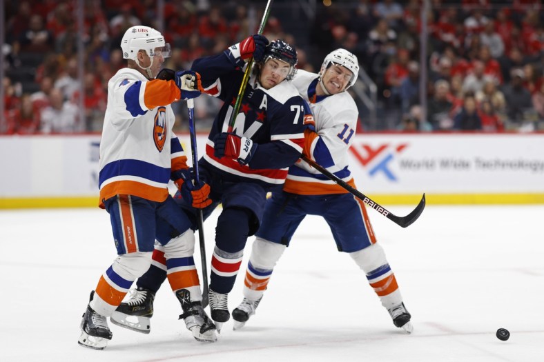 Apr 26, 2022; Washington, District of Columbia, USA; Washington Capitals right wing T.J. Oshie (77) battle for the puck with New York Islanders defenseman Andy Greene (4)  and Islanders left wing Zach Parise (11) in the third period at Capital One Arena. Mandatory Credit: Geoff Burke-USA TODAY Sports