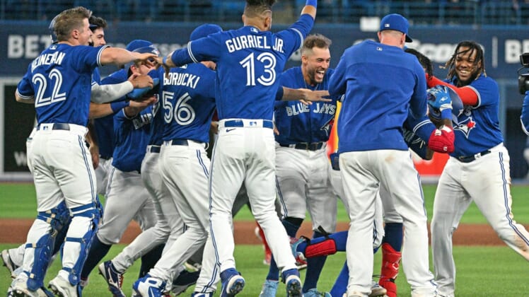 Apr 26, 2022; Toronto, Ontario, CAN;  Toronto Blue Jays players surround left fielder Raimel Tapia as they celebrate his walk off sacrifice fly that scored the winning run against the Boston Red Sox in the 10th inning at Rogers Centre. Mandatory Credit: Dan Hamilton-USA TODAY Sports