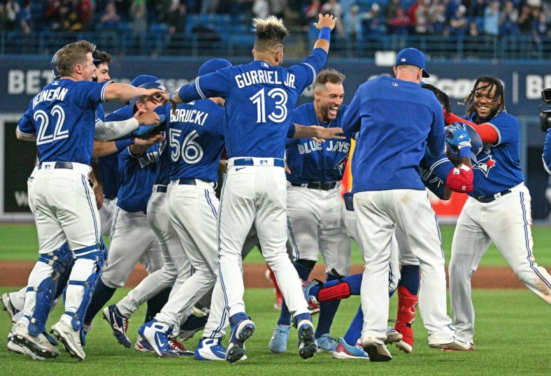 Apr 26, 2022; Toronto, Ontario, CAN;  Toronto Blue Jays players surround left fielder Raimel Tapia as they celebrate his walk off sacrifice fly that scored the winning run against the Boston Red Sox in the 10th inning at Rogers Centre. Mandatory Credit: Dan Hamilton-USA TODAY Sports
