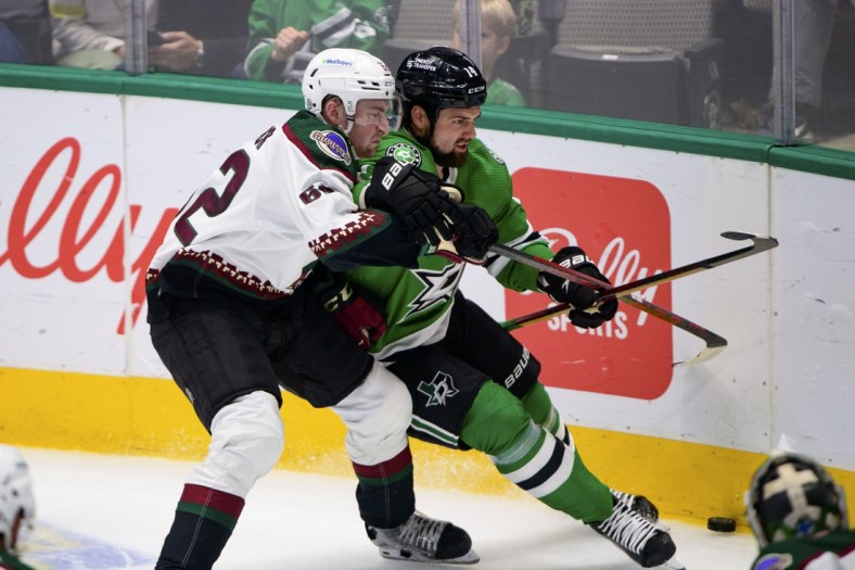 Apr 27, 2022; Dallas, Texas, USA; Dallas Stars left wing Jamie Benn (14) and Arizona Coyotes defenseman J.J. Moser (62) chase the puck during the second period at the American Airlines Center. Mandatory Credit: Jerome Miron-USA TODAY Sports