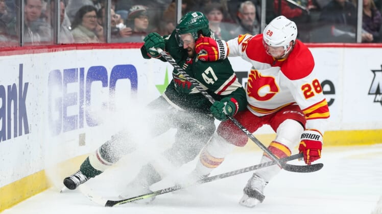 Apr 28, 2022; Saint Paul, Minnesota, USA; Minnesota Wild defenseman Alex Goligoski (47) and Calgary Flames center Elias Lindholm (28) compete for the puck in the first period at Xcel Energy Center. Mandatory Credit: David Berding-USA TODAY Sports
