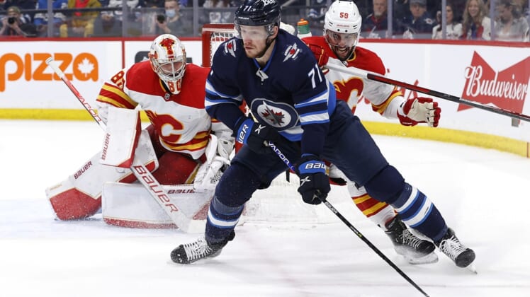 Apr 29, 2022; Winnipeg, Manitoba, CAN; Winnipeg Jets left wing Evgeny Svechnikov (71) is checked by Calgary Flames defenseman Oliver Kylington (58) in front of Calgary Flames goaltender Dan Vladar (80) in the second period at Canada Life Centre. Mandatory Credit: James Carey Lauder-USA TODAY Sports