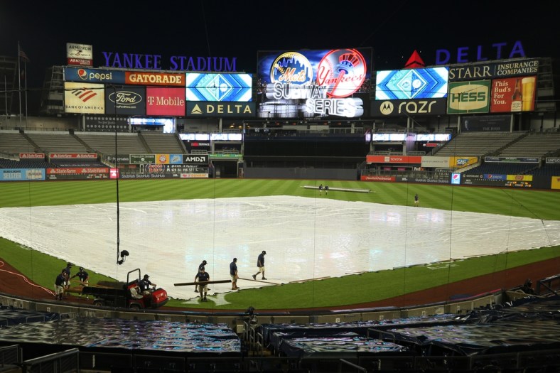 Aug 28, 2020; Bronx, New York, USA; Grounds crew members remove the tarp from the infield after a rain delay before the start of the second game of a double header between the New York Yankees and the New York Mets at Yankee Stadium. Mandatory Credit: Brad Penner-USA TODAY Sports