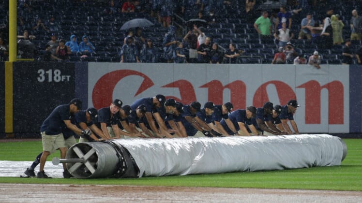 Jul 17, 2021; Bronx, New York, USA; Members of the grounds crew roll the tarp onto the infield during a rain delay during the seventh inning between the New York Yankees and the Boston Red Sox at Yankee Stadium. The game was later called and the Yankees won in six innings. Mandatory Credit: Brad Penner-USA TODAY Sports