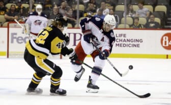Sep 27, 2021; Pittsburgh, Pennsylvania, USA;  Columbus Blue Jackets defenseman Scott Harrington (4) shoots the puck up ice against Pittsburgh Penguins defenseman Taylor Fedun (42) during the second period at PPG Paints Arena. Mandatory Credit: Charles LeClaire-USA TODAY Sports