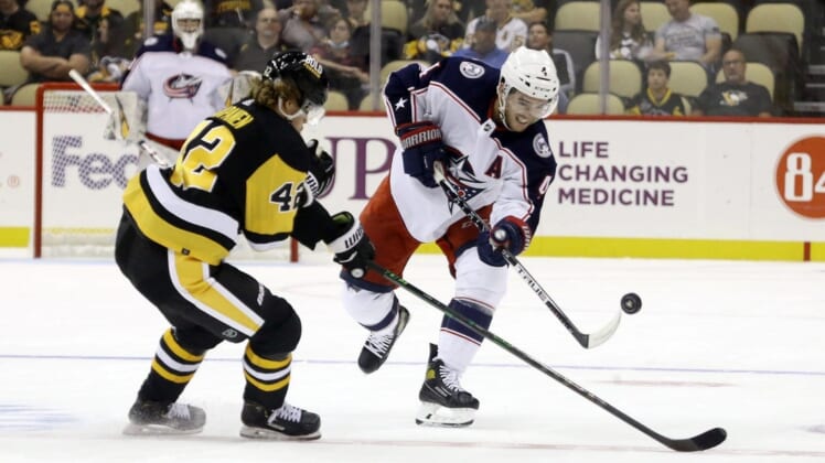 Sep 27, 2021; Pittsburgh, Pennsylvania, USA;  Columbus Blue Jackets defenseman Scott Harrington (4) shoots the puck up ice against Pittsburgh Penguins defenseman Taylor Fedun (42) during the second period at PPG Paints Arena. Mandatory Credit: Charles LeClaire-USA TODAY Sports