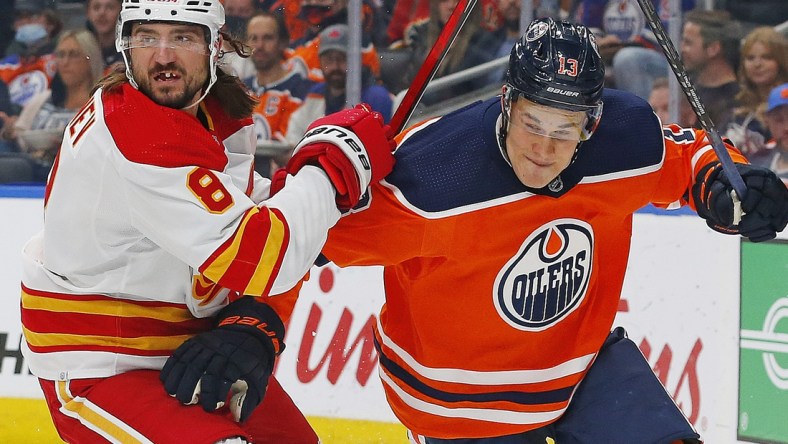 Oct 4, 2021; Edmonton, Alberta, CAN; Calgary Flames defensemen Chris Tanev (8) and Edmonton Oilers forward Jesse Puljujarvi (13) battle for a loose puck during the first period at Rogers Place. Mandatory Credit: Perry Nelson-USA TODAY Sports