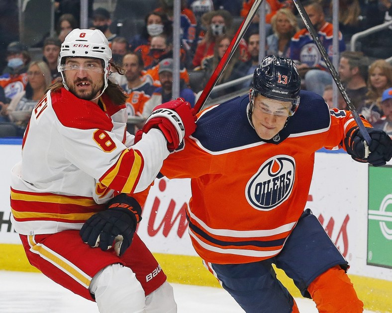 Oct 4, 2021; Edmonton, Alberta, CAN; Calgary Flames defensemen Chris Tanev (8) and Edmonton Oilers forward Jesse Puljujarvi (13) battle for a loose puck during the first period at Rogers Place. Mandatory Credit: Perry Nelson-USA TODAY Sports