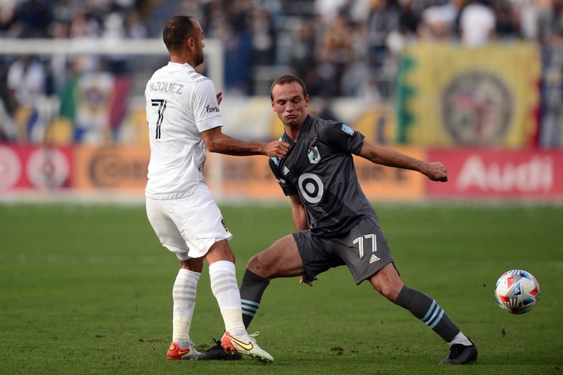 Nov 7, 2021; Carson, California, USA; Minnesota United defender Chase Gasper (77) and Los Angeles Galaxy midfielder Victor Vazquez (7) go for a loose ball during the first half at Dignity Health Sports Park. Mandatory Credit: Joe Camporeale-USA TODAY Sports