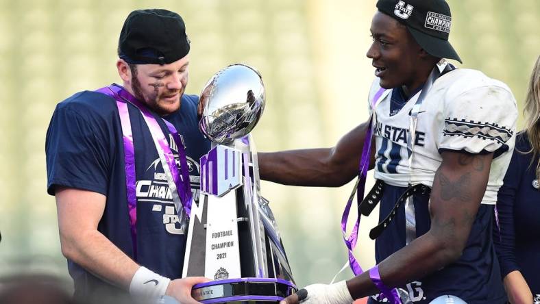 Dec 4, 2021; Carson, CA, USA; Utah State Aggies quarterback Logan Bonner (1) and defensive end Byron Vaughns (11) hold the champions trophy following the victory against the San Diego State Aztecs in the Mountain West Conference championship game at Dignity Health Sports Park. Mandatory Credit: Gary A. Vasquez-USA TODAY Sports