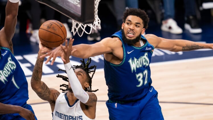 Apr 29, 2022; Minneapolis, Minnesota, USA; Minnesota Timberwolves center Karl-Anthony Towns (32) blocks Memphis Grizzlies guard Ja Morant (12) in the fourth quarter during game six of the first round for the 2022 NBA playoffs at Target Center. Mandatory Credit: Brad Rempel-USA TODAY Sports