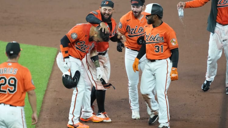 Apr 30, 2022; Baltimore, Maryland, USA; Baltimore Orioles catcher Robinson Chirinos (23) greeted by second baseman Rougned Odor (12), Ryan McKenna (26) and Cedric Mullins (31) following his game winning bunt in the tenth inning against the Boston Red Sox at Oriole Park at Camden Yards. Mandatory Credit: Mitch Stringer-USA TODAY Sports