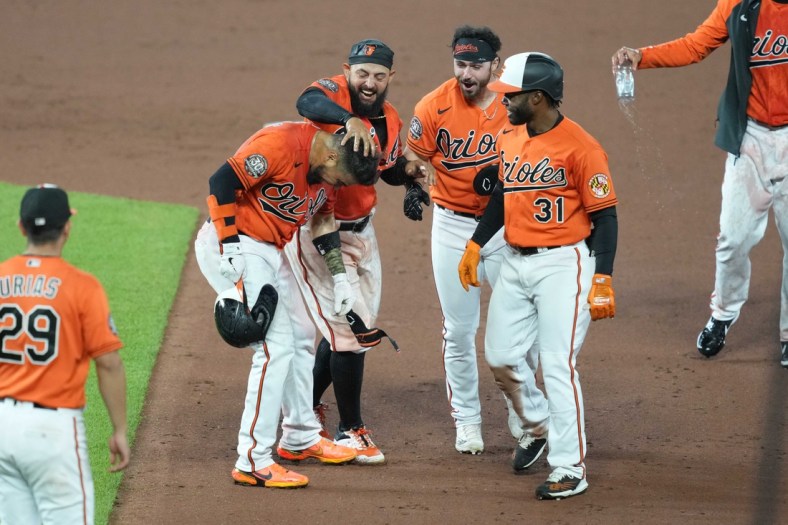 Apr 30, 2022; Baltimore, Maryland, USA; Baltimore Orioles catcher Robinson Chirinos (23) greeted by second baseman Rougned Odor (12), Ryan McKenna (26) and Cedric Mullins (31) following his game winning bunt in the tenth inning against the Boston Red Sox at Oriole Park at Camden Yards. Mandatory Credit: Mitch Stringer-USA TODAY Sports
