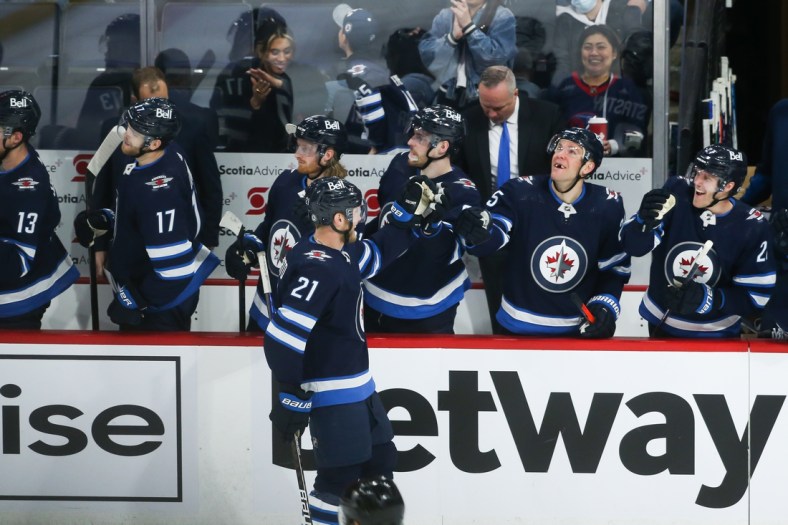 May 1, 2022; Winnipeg, Manitoba, CAN;  Winnipeg Jets forward Dominic Toninato (21) is congratulated by his team mates on his goal against Seattle Kraken goalie Chris Driedger (60) during the third period at Canada Life Centre. Mandatory Credit: Terrence Lee-USA TODAY Sports