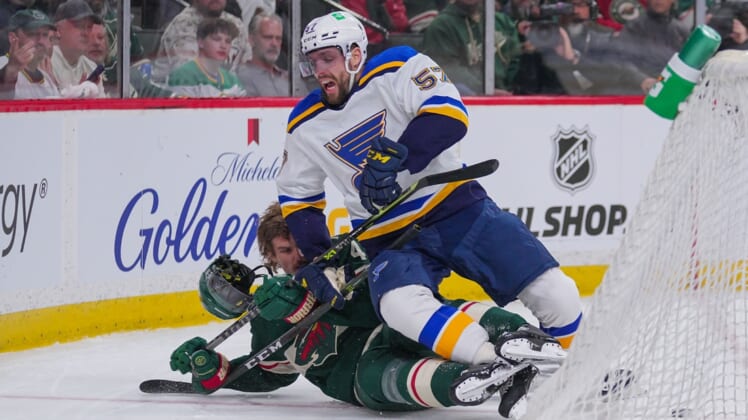 May 2, 2022; Saint Paul, Minnesota, USA; St. Louis Blues left wing David Perron (57) checks Minnesota Wild defenseman Jon Merrill (4) in the first period in game one of the first round of the 2022 Stanley Cup Playoffs at Xcel Energy Center. Mandatory Credit: Brad Rempel-USA TODAY Sports