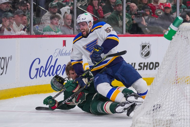 May 2, 2022; Saint Paul, Minnesota, USA; St. Louis Blues left wing David Perron (57) checks Minnesota Wild defenseman Jon Merrill (4) in the first period in game one of the first round of the 2022 Stanley Cup Playoffs at Xcel Energy Center. Mandatory Credit: Brad Rempel-USA TODAY Sports