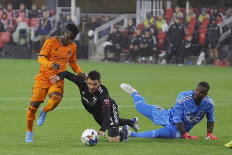 May 7, 2022; Washington, District of Columbia, USA; Houston Dynamo forward Carlos Darwin Quintero (23) dribbles the ball past D.C. United defender Brendan Hines-Ike (4) as D.C. United goalkeeper Bill Hamid (28) chases in the first half at Audi Field. Mandatory Credit: Geoff Burke-USA TODAY Sports