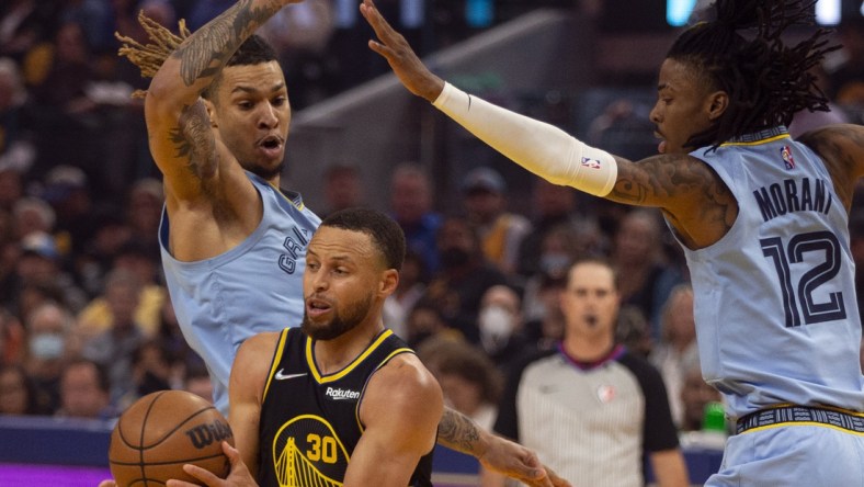 May 7, 2022; San Francisco, California, USA; Golden State Warriors guard Stephen Curry (30) drives between Memphis Grizzlies forward Brandon Clarke (15) and guard Ja Morant (12) during the first half of game three of the second round for the 2022 NBA playoffs at Chase Center. Mandatory Credit: D. Ross Cameron-USA TODAY Sports