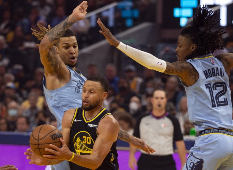 May 7, 2022; San Francisco, California, USA; Golden State Warriors guard Stephen Curry (30) drives between Memphis Grizzlies forward Brandon Clarke (15) and guard Ja Morant (12) during the first half of game three of the second round for the 2022 NBA playoffs at Chase Center. Mandatory Credit: D. Ross Cameron-USA TODAY Sports