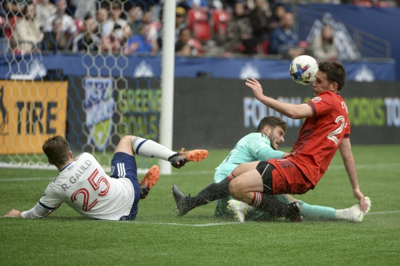 May 8, 2022; Vancouver, British Columbia, CAN; Toronto FC goalkeeper Alex Bono (25) and defender Shane O'Neill (27) defend against Vancouver Whitecaps midfielder Ryan Gauld (25) during the first half at BC Place. Mandatory Credit: Anne-Marie Sorvin-USA TODAY Sports