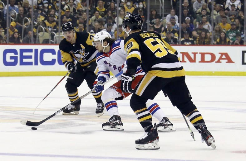 May 13, 2022; Pittsburgh, Pennsylvania, USA;  New York Rangers left wing Artemi Panarin (10) moves the puck between Pittsburgh Penguins center Evgeni Malkin (71) and left wing Jake Guentzel (59) during the first period in game six of the first round of the 2022 Stanley Cup Playoffs at PPG Paints Arena. Mandatory Credit: Charles LeClaire-USA TODAY Sports