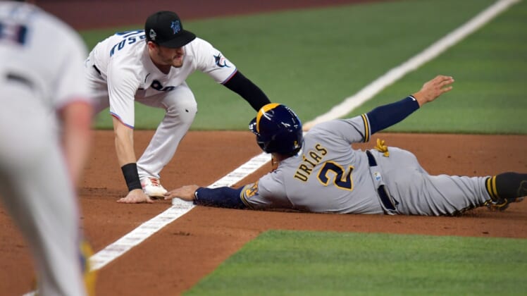 May 14, 2022; Miami, Florida, USA; Milwaukee Brewers shortstop Luis Urias (2) dives into third base ahead of the tag by Miami Marlins third baseman Brian Anderson (15) during the third inning at loanDepot Park. Mandatory Credit: Jim Rassol-USA TODAY Sports