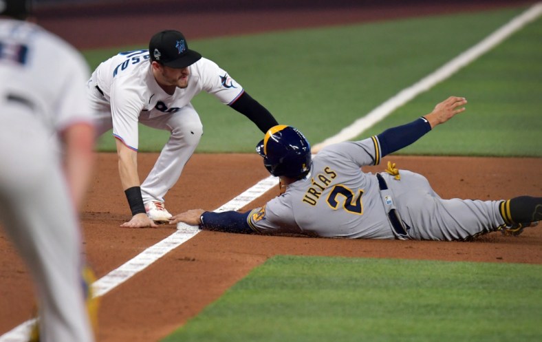 May 14, 2022; Miami, Florida, USA; Milwaukee Brewers shortstop Luis Urias (2) dives into third base ahead of the tag by Miami Marlins third baseman Brian Anderson (15) during the third inning at loanDepot Park. Mandatory Credit: Jim Rassol-USA TODAY Sports