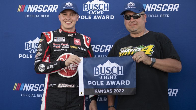 May 14, 2022; Kansas City, Kansas, USA; NASCAR Cup Series driver Christopher Bell (left) reacts after securing the pole position during AdventHealth 400 qualifying at Kansas Speedway. Mandatory Credit: Amy Kontras-USA TODAY Sports