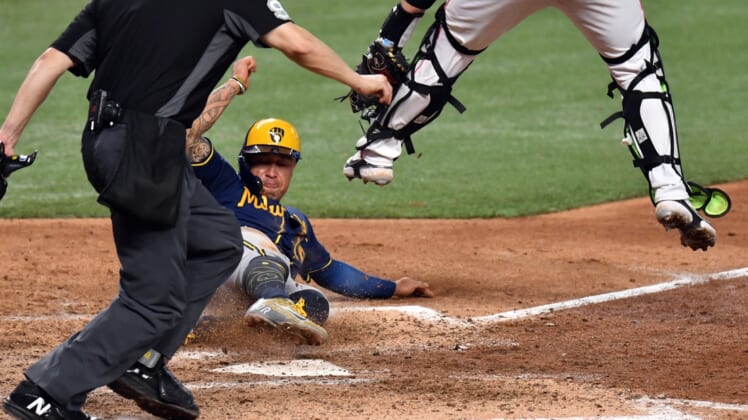May 15, 2022; Miami, Florida, USA; Milwaukee Brewers Kolten Wong (16) slides under the tag of Miami Marlins catcher Payton Henry (59) during the eighth inning at loanDepot Park. Mandatory Credit: Jim Rassol-USA TODAY Sports