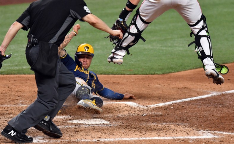 May 15, 2022; Miami, Florida, USA; Milwaukee Brewers Kolten Wong (16) slides under the tag of Miami Marlins catcher Payton Henry (59) during the eighth inning at loanDepot Park. Mandatory Credit: Jim Rassol-USA TODAY Sports