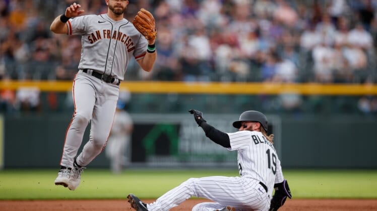 May 16, 2022; Denver, Colorado, USA; San Francisco Giants third baseman Evan Longoria (10) jumps to avoid Colorado Rockies designated hitter Charlie Blackmon (19) as he slides into third advancing on a wild pitch in the first inning at Coors Field. Mandatory Credit: Isaiah J. Downing-USA TODAY Sports