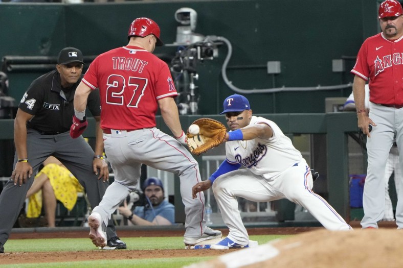 May 17, 2022; Arlington, Texas, USA; Los Angeles Angels center fielder Mike Trout (27) beats the throw to Texas Rangers first baseman Andy Ibanez (77) on a pick off attempt during the fifth inning of a baseball game at Globe Life Field. Mandatory Credit: Jim Cowsert-USA TODAY Sports