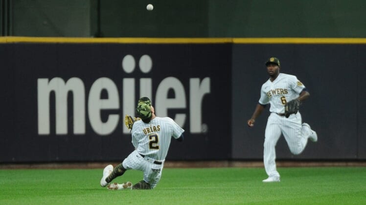 May 21, 2022; Milwaukee, Wisconsin, USA; Milwaukee Brewers shortstop Luis Urias (2) catches a fly ball as center fielder Lorenzo Cain (6) backs up the play against the Washington Nationals in the first inning at American Family Field. Mandatory Credit: Michael McLoone-USA TODAY Sports