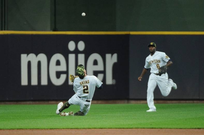May 21, 2022; Milwaukee, Wisconsin, USA; Milwaukee Brewers shortstop Luis Urias (2) catches a fly ball as center fielder Lorenzo Cain (6) backs up the play against the Washington Nationals in the first inning at American Family Field. Mandatory Credit: Michael McLoone-USA TODAY Sports