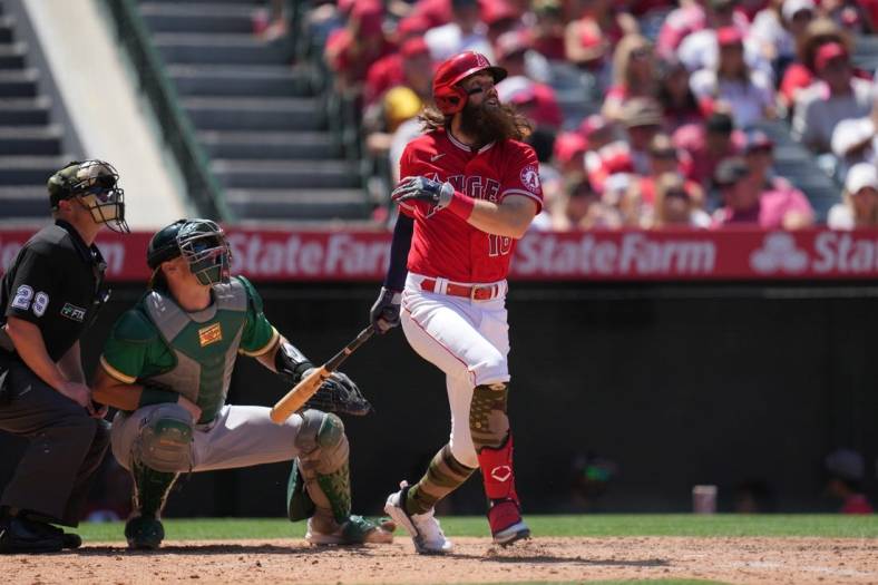 May 22, 2022; Anaheim, California, USA; Los Angeles Angels left fielder Brandon Marsh (16) follows through on a run-scoring single in the fifth inning as Oakland Athletics catcher Sean Murphy (12) and umpire Sean Barber (29) watch at Angel Stadium. Mandatory Credit: Kirby Lee-USA TODAY Sports