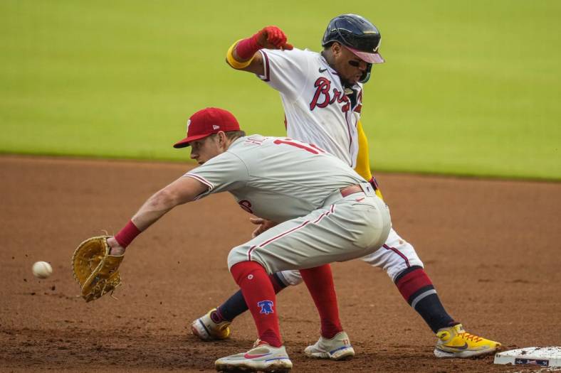 May 24, 2022; Cumberland, Georgia, USA; Atlanta Braves right fielder Ronald Acuna Jr. (13) beats a pick off throw to Philadelphia Phillies first baseman Rhys Hoskins (17) during the first inning at Truist Park. Mandatory Credit: Dale Zanine-USA TODAY Sports
