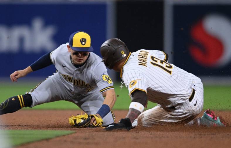 May 24, 2022; San Diego, California, USA; San Diego Padres third baseman Manny Machado (13) is tagged out by Milwaukee Brewers shortstop Luis Urias (2) attempting to steal second base during the fifth inning at Petco Park. Mandatory Credit: Orlando Ramirez-USA TODAY Sports