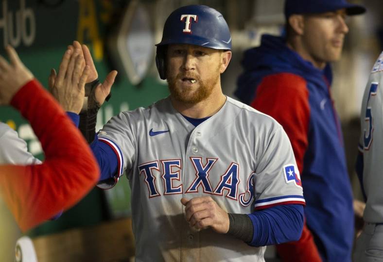 May 27, 2022; Oakland, California, USA; Texas Rangers right fielder Kole Calhoun gets high fives from his teammates after scoring on a double by Nathaniel Lowe during the seventh inning against the Oakland Athletics at RingCentral Coliseum. Mandatory Credit: D. Ross Cameron-USA TODAY Sports