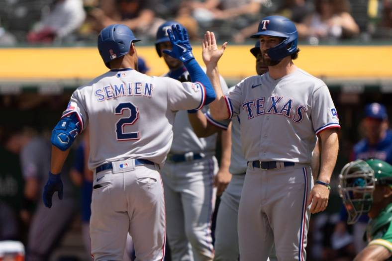 May 28, 2022; Oakland, California, USA; Texas Rangers second baseman Marcus Semien (2) celebrates with third baseman Charlie Culberson (11) after hitting a grand slam during the fifth inning against the Oakland Athletics at RingCentral Coliseum. Mandatory Credit: Stan Szeto-USA TODAY Sports