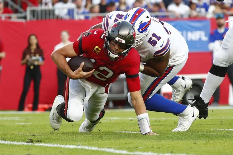Dec 12, 2021; Tampa, Florida, USA; Tampa Bay Buccaneers quarterback Tom Brady (12) runs with the ball as Buffalo Bills defensive end Bryan Cox (51) defends during the first half at Raymond James Stadium. Mandatory Credit: Kim Klement-USA TODAY Sports