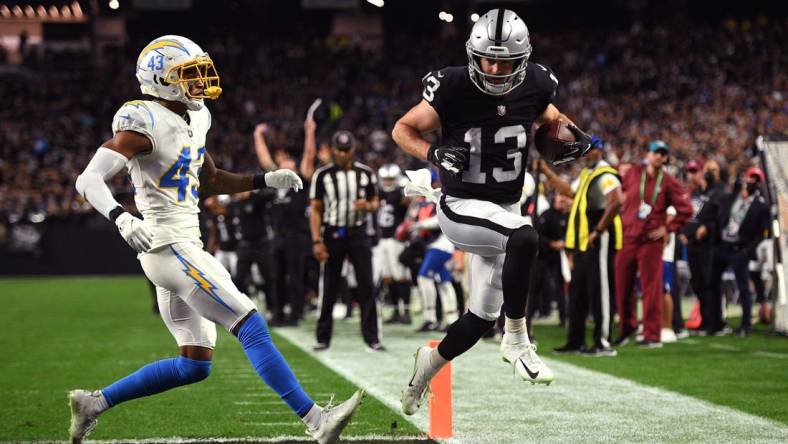 Jan 9, 2022; Paradise, Nevada, USA; Las Vegas Raiders wide receiver Hunter Renfrow (13) scores a touchdown ahead of Los Angeles Chargers cornerback Michael Davis (43) during the first quarter at Allegiant Stadium. Mandatory Credit: Orlando Ramirez-USA TODAY Sports