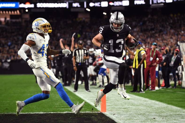 Jan 9, 2022; Paradise, Nevada, USA; Las Vegas Raiders wide receiver Hunter Renfrow (13) scores a touchdown ahead of Los Angeles Chargers cornerback Michael Davis (43) during the first quarter at Allegiant Stadium. Mandatory Credit: Orlando Ramirez-USA TODAY Sports