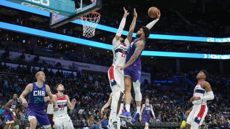 Apr 10, 2022; Charlotte, North Carolina, USA; Charlotte Hornets forward Miles Bridges (0) goes for the dunk defended by Washington Wizards center Daniel Gafford (21) during the second half at Spectrum Center. Mandatory Credit: Jim Dedmon-USA TODAY Sports