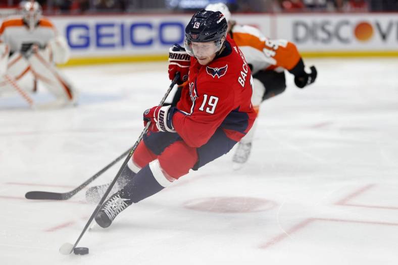 Apr 12, 2022; Washington, District of Columbia, USA; Washington Capitals center Nicklas Backstrom (19) skates with the puck as Philadelphia Flyers left wing Noah Cates (49) chases in the third period in the third period at Capital One Arena. Mandatory Credit: Geoff Burke-USA TODAY Sports