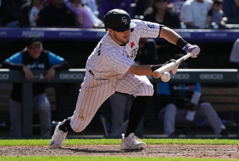 May 30, 2022; Denver, Colorado, USA; Colorado Rockies shortstop Garrett Hampson (1) singles on a bunt in the seventh inning against the Miami Marlins at Coors Field. Mandatory Credit: Ron Chenoy-USA TODAY Sports
