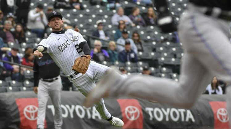 Jun 1, 2022; Denver, Colorado, USA; Colorado Rockies second baseman Ryan McMahon (left) attempts to throw out Miami Marlins third baseman Luke Williams (right) after a bunt during the second inning at Coors Field. Mandatory Credit: John Leyba-USA TODAY Sports
