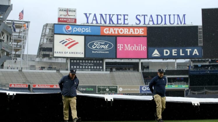 Jun 1, 2022; Bronx, New York, USA; Members of the grounds crew pull the tarp across the field after batting practice before a game between the New York Yankees and the Los Angeles Angels at Yankee Stadium. Mandatory Credit: Brad Penner-USA TODAY Sports
